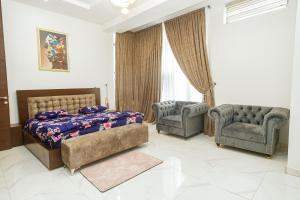 um quarto com uma cama, 2 cadeiras e um sofá em Teleworld Apartment em Ikeja