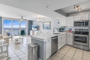 a kitchen with white cabinets and a view of the ocean at Pelican Beach Resort by Tufan in Destin