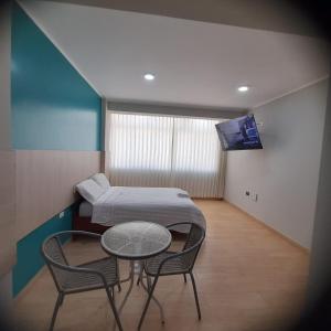 Habitación hospitalaria con cama, mesa y sillas en Hostal Tulipán Rojo en Lambayeque