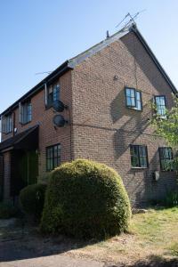 an old brick building with a bush in front of it at Apartment in the heart of Old Town Beaconsfield in Buckinghamshire