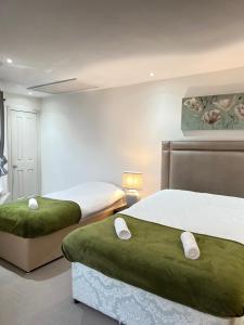1 Schlafzimmer mit 2 Betten und grüner Bettwäsche in der Unterkunft Fulham suites in London