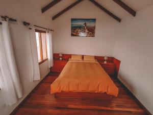 a bedroom with a bed with an orange blanket at Ecolodge Santo Campo in Isla de Sol