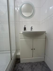 W białej łazience znajduje się umywalka i lustro. w obiekcie Modern 2-Bed Gem! Prime M22 Location Near Airport, Hospital & Sleeps 7 w mieście Wythenshawe
