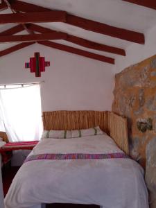 uma cama num quarto com uma parede de pedra em INTI WASI LODGE em Comunidad Yumani