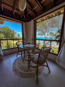 um quarto com uma mesa, cadeiras e janelas em Pousada Santo Mar em Arraial d'Ajuda