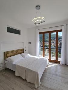 a white bedroom with a bed and a large window at Villa Mafalda in Pietra Ligure