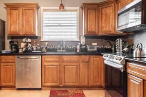 uma cozinha com armários de madeira e uma máquina de lavar louça em aço inoxidável em Quiet Cozy 3bedroom home 10 minutes from Downtown em Nova Orleães