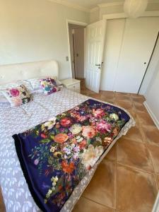 Un dormitorio con una cama con una manta floral. en Maitencillo! Depto A 5 min a pie de la playa!, en Maitencillo