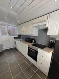 uma cozinha com armários brancos e um forno com placa de fogão em Anstuns LODGE em Liverpool