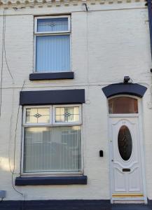 a white building with two windows and a door at Anstuns LODGE in Liverpool