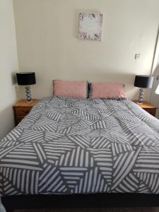 a bed with a black and white comforter and two lamps at Anstuns LODGE in Liverpool