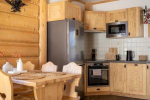 a kitchen with a table and a stainless steel refrigerator at Lux-HOUSE & JACUZZI SAUNA in Zakopane