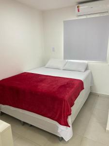 a bedroom with a white bed with a red blanket at Flats Sol e Mar in São José da Coroa Grande