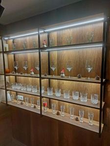 une étagère remplie de verres à vin sur un mur dans l'établissement Vikendica Tuzla, Dolina mira, à Tuzla