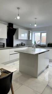 a white kitchen with a large island in the middle at Brand New 3 bedroom House in Gated Development! in Polesworth