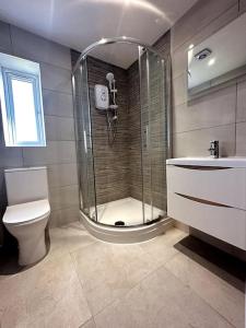 a bathroom with a shower and a toilet and a sink at Brand New 3 bedroom House in Gated Development! in Polesworth