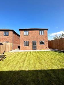 a brick house with a grassy yard in front of it at Brand New 3 bedroom House in Gated Development! in Polesworth