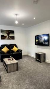 a living room with a black couch and a tv at Brand New 3 bedroom House in Gated Development! in Polesworth