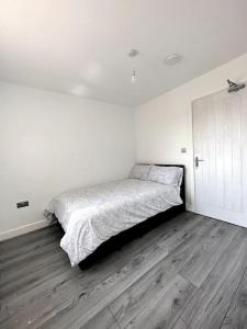 a white bedroom with a bed and a wooden floor at Brand New 3 bedroom House in Gated Development! in Polesworth