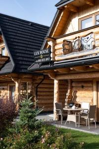 a log house with a table and chairs in front of it at Lux-HOUSE & JACUZZI SAUNA in Zakopane