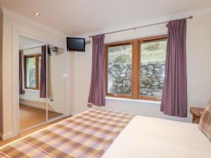 a bedroom with a bed and two windows at Tigh na Creag in Sconser