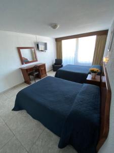 a hotel room with two beds and a desk at Hotel Qualitel Plus in Morelia
