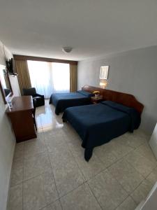 Habitación de hotel con 2 camas y mesa en Hotel Qualitel Plus en Morelia