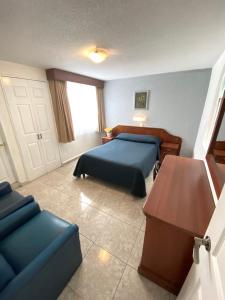 een slaapkamer met een bed, een bank en een tafel bij Hotel Qualitel Plus in Morelia