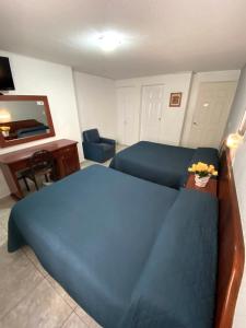 a bedroom with a blue bed and a desk at Hotel Qualitel Plus in Morelia