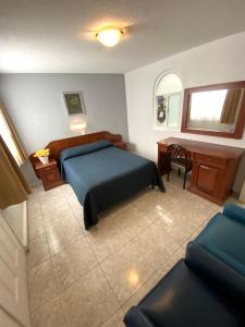 a bedroom with a blue bed and a desk at Hotel Qualitel Plus in Morelia
