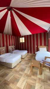 two beds in a room with a red and white tent at Rest luxury camp in Disah
