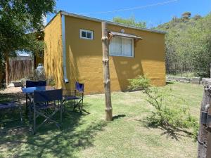 a yellow house with a table and chairs in the yard at Cabañas Llitulun in Alpa Corral