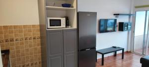 a kitchen with a refrigerator and a microwave on a shelf at 5 min walk from Yumbo 310 in Playa del Ingles