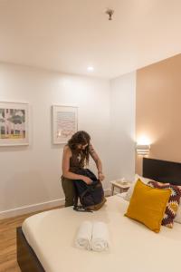 una donna seduta su un letto con una borsa di Auberge Saintlo Montréal Hostel a Montréal
