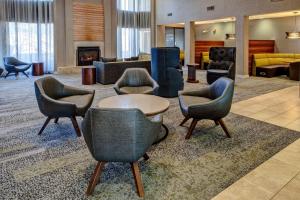 a lobby with chairs and a table and a fireplace at Courtyard Chicago St. Charles in Saint Charles