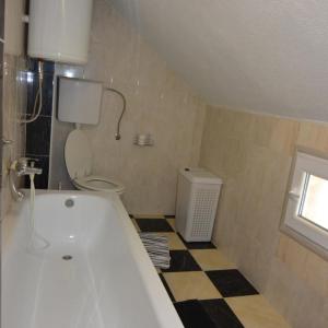 baño con bañera, aseo y ventana en Apartman Armenia, en Vrnjci