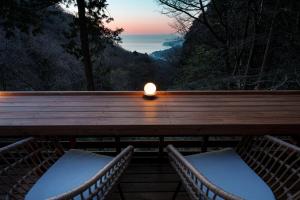 une bougie assise sur une terrasse avec deux chaises dans l'établissement AMAO VILLA 熱海, à Atami