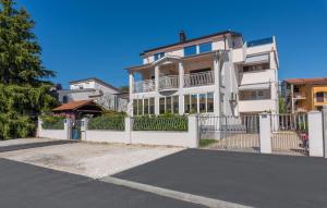 a white house with a white fence and a street at Apartments Viktor in Poreč