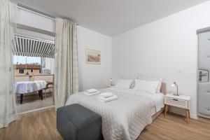 a white bedroom with a bed and a table at Apartments Viktor in Poreč