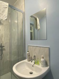 a bathroom sink with a shower and a mirror at Abbie Lodge Guest House in Weston-super-Mare