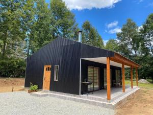 a black shed with a porch and a wooden door at Valdivia Tralcao Lodge 2 in Valdivia