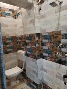 a bathroom with a toilet and a tiled wall at Varanasi homestay in Varanasi