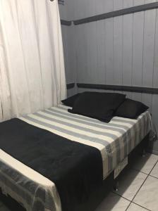 - un lit avec une couverture et des oreillers noirs et blancs dans l'établissement Aluguel casa para temporada, à Itapema