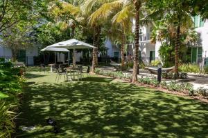 césped con sombrilla, mesa y sillas en Beachside Bliss 1BR Oasis + Pool in Ft Lauderdale, en Fort Lauderdale