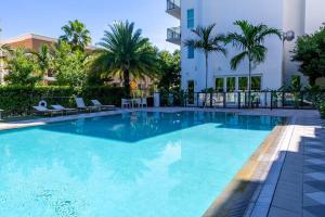 una gran piscina con palmeras y un edificio en Beachside Bliss 1BR Oasis + Pool in Ft Lauderdale, en Fort Lauderdale