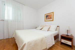 a white bedroom with a white bed and a window at Apartments Olive sea view in Mimice +46 photos