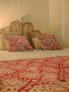 een bed met 4 kussens en een rode deken bij Appartement cosy Cotonou 1 chambre in Cotonou