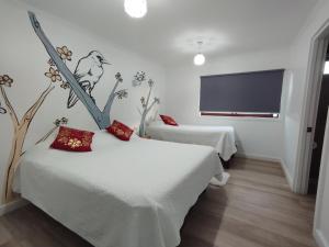 a bedroom with two beds and a tv on the wall at HOSTAL LA MODERNA in Quintero