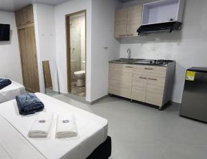 um quarto com 2 camas e uma cozinha com um lavatório em Aparta estudios Estadio la 80 em Medellín