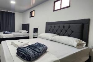 um quarto com 2 camas com lençóis brancos e uma cabeceira em Aparta estudios Estadio la 80 em Medellín